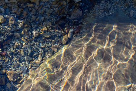 Pebbles and sand seen through rippling water.
