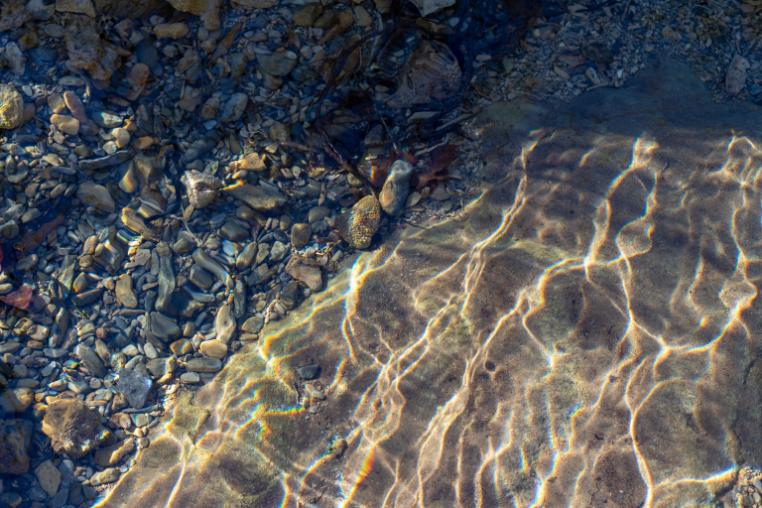 Pebbles and sand seen through rippling water.